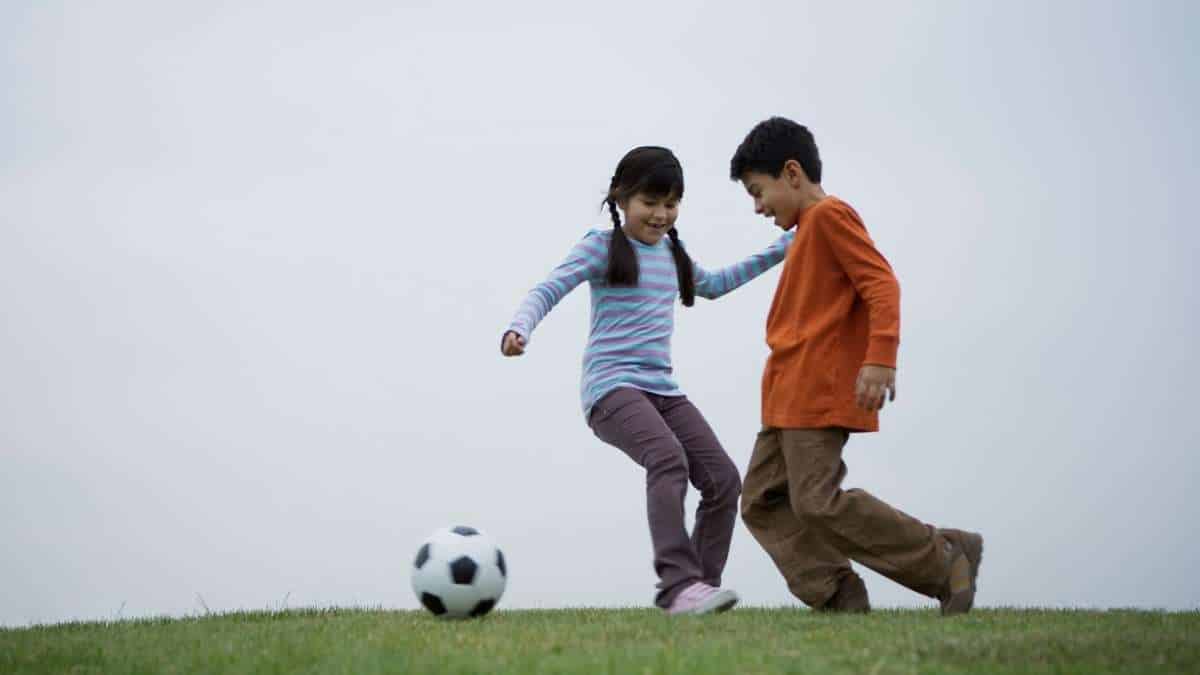 menina e menino jogando futebol juntos